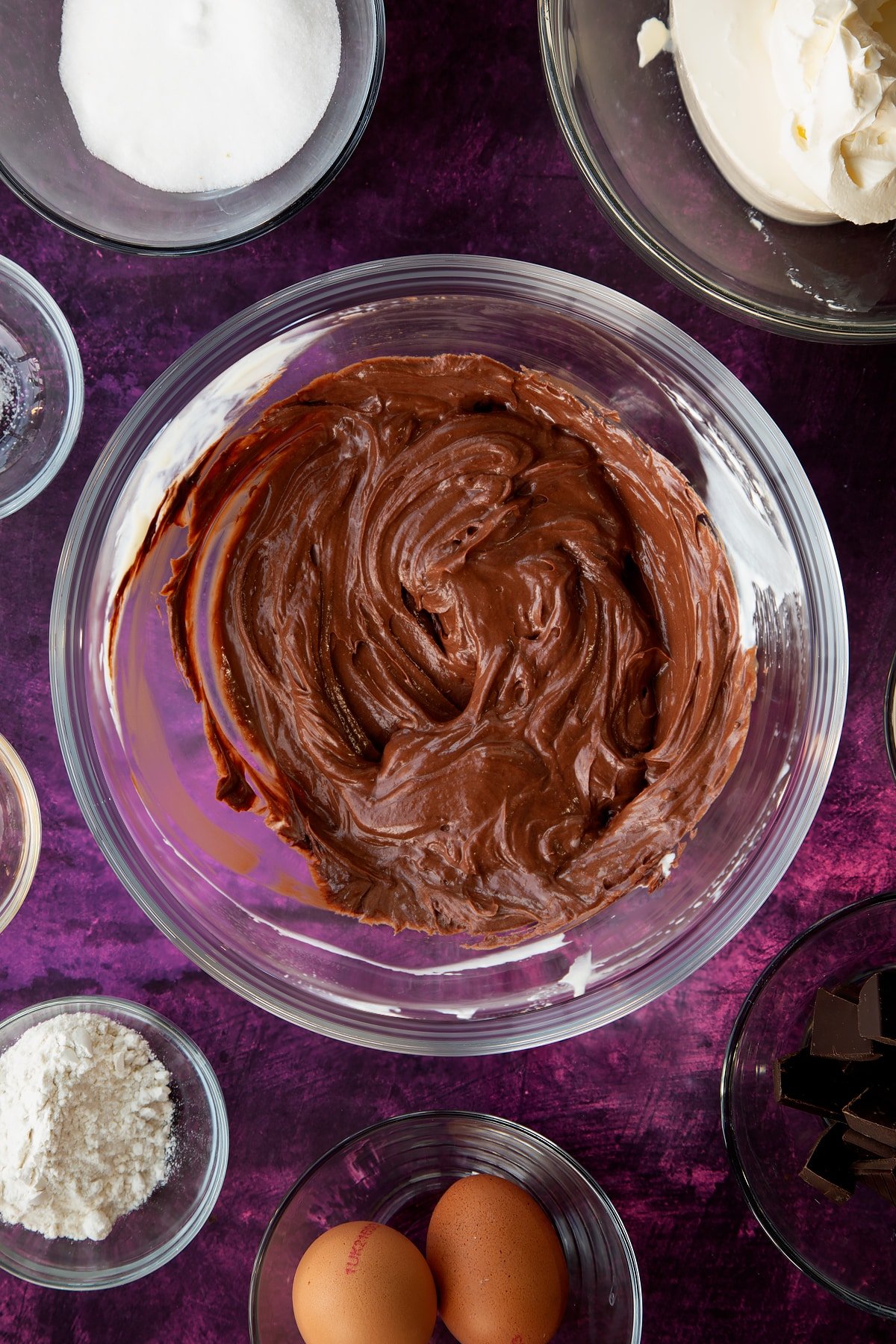 Mixing the chocolate marble cheesecake mixture together in a glass mixing bowl.