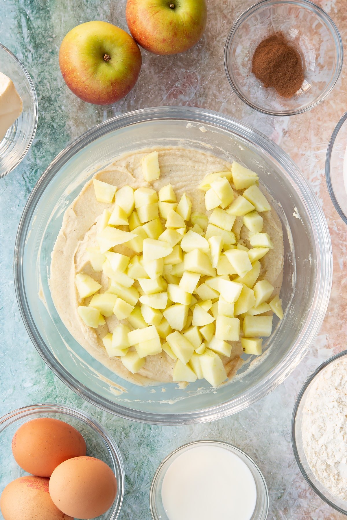 Adding sliced apples into the mixing bowl of cake ingredients.