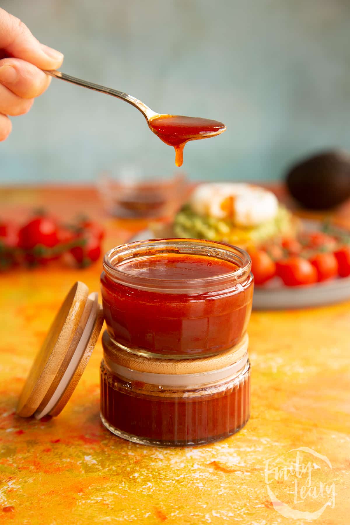 A spoon of homemade chipotle dressing with a pot of the dressing below.