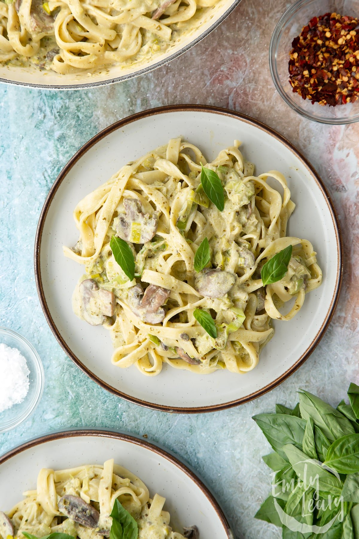 Finished leek and pesto pasta served on a white decorative plate.