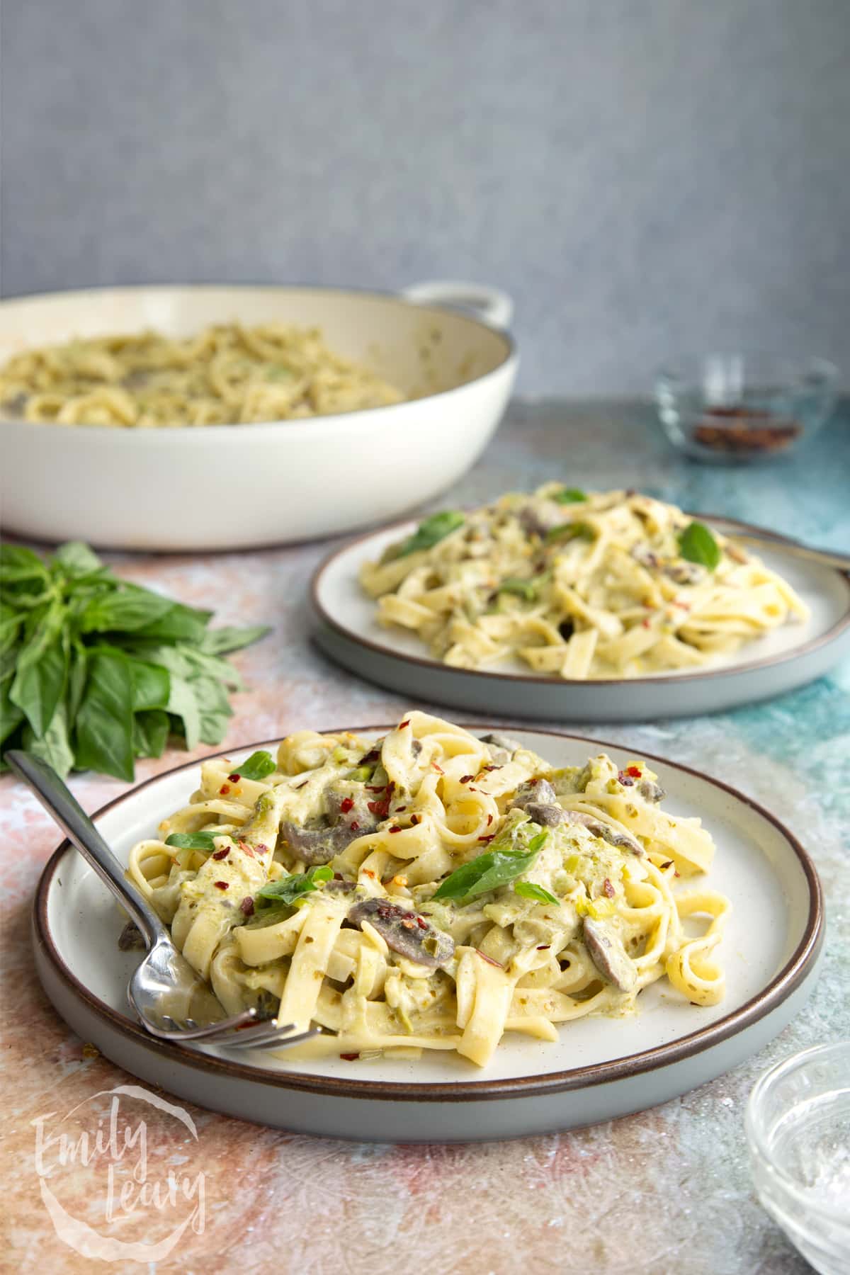 Side on shot of the finished leek and pesto pasta served on a decoative plate.