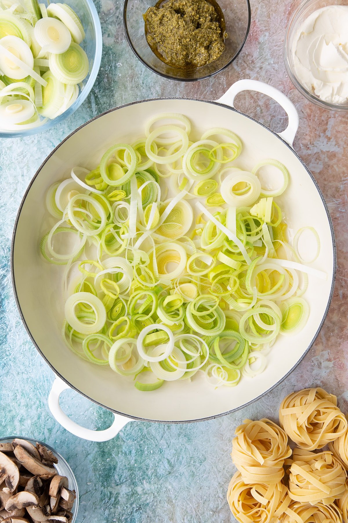 Adding sliced leeks into a large pan.