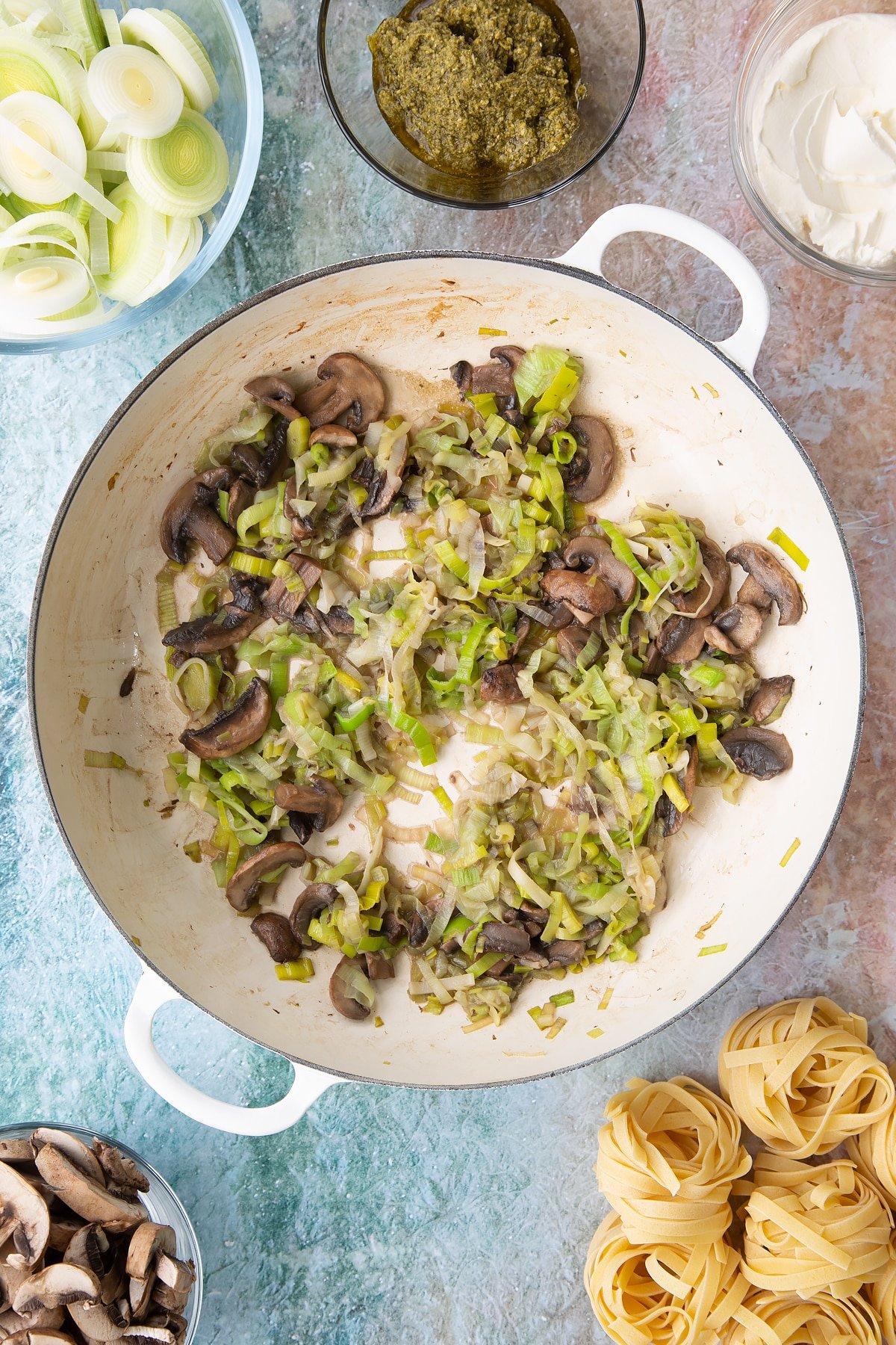 Mixing the softened mushrooms and leeks together in a pan.