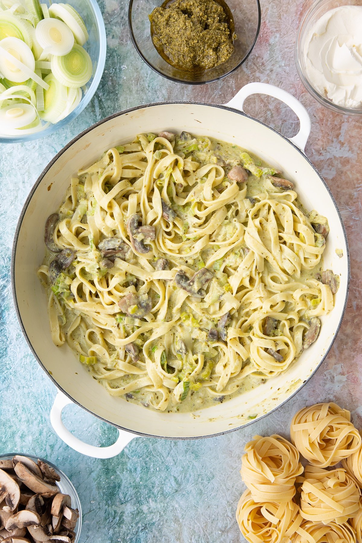 Mixing together the leek and pesto pasta ingredients in a pan.