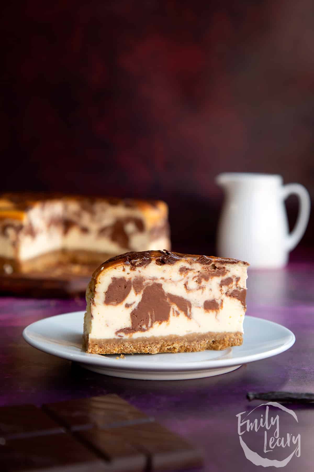 Finished slice of marble cheesecake on a white decorative plate.