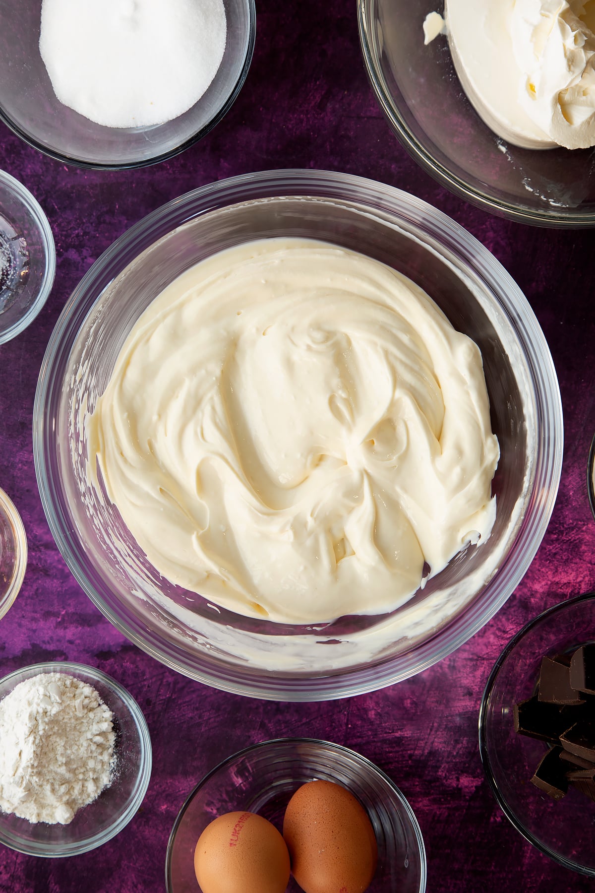 Stiring the marble cheesecake mixture together in a glass mixing bowl.