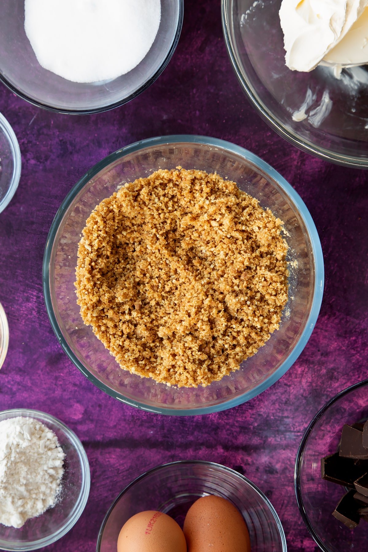 Mixing the melted butter and crumbled biscuits together in a mixing bowl.