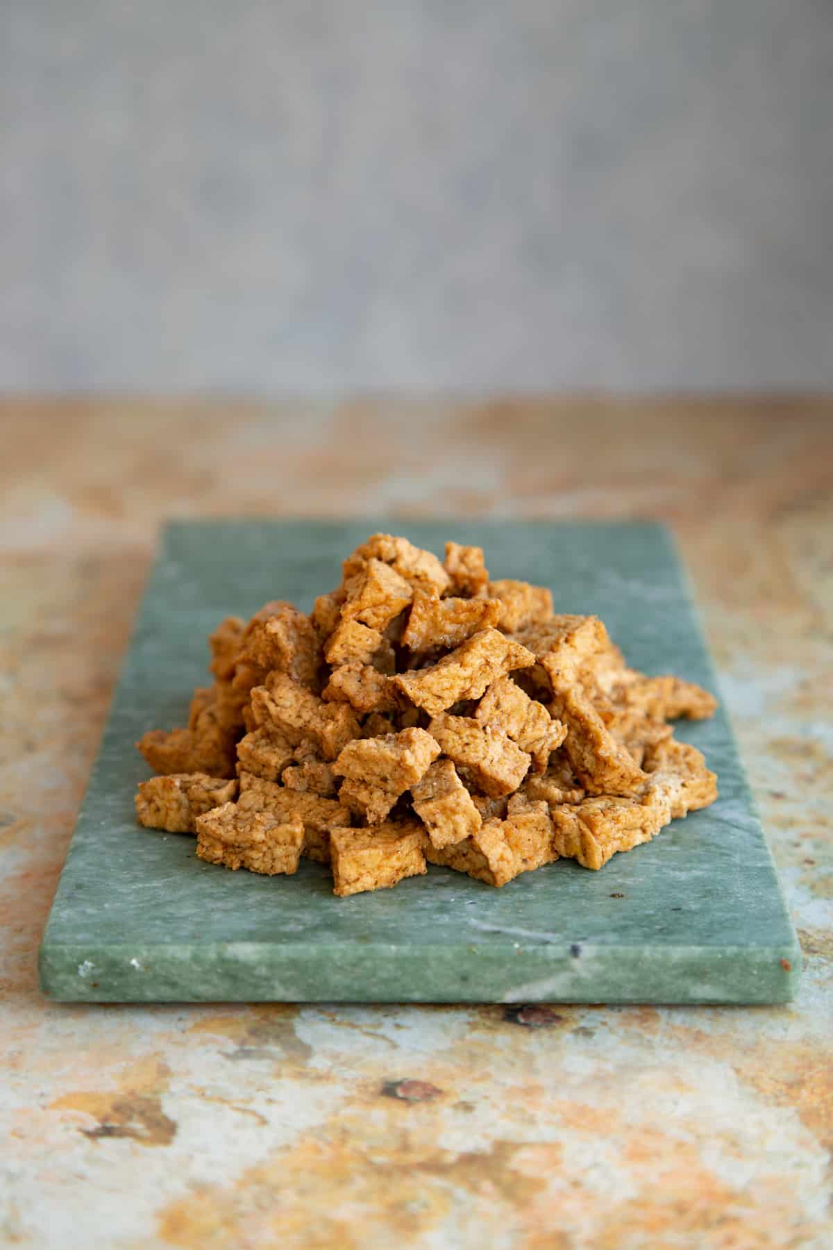 marinated tofy pieces on a green marble cutting board,