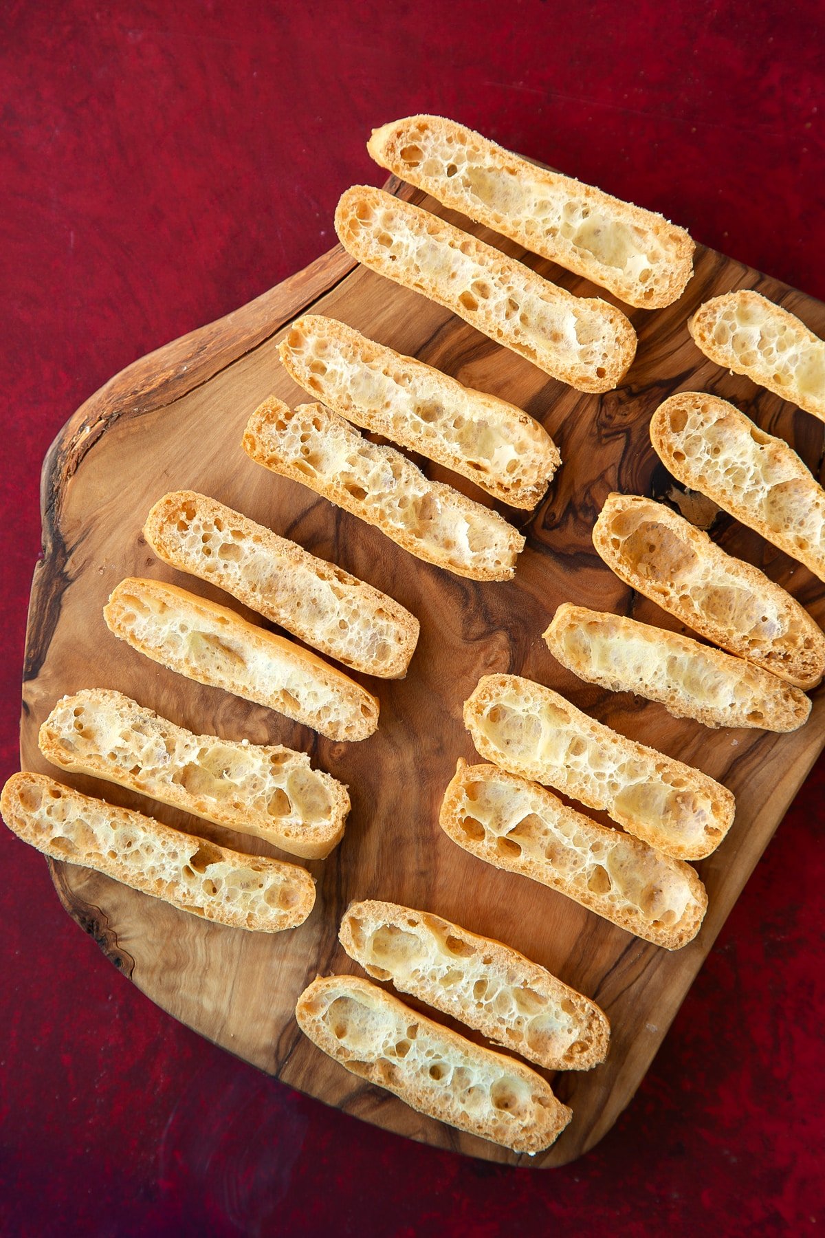 Overhead shot of the cut open mini eclairs on a wooden board.