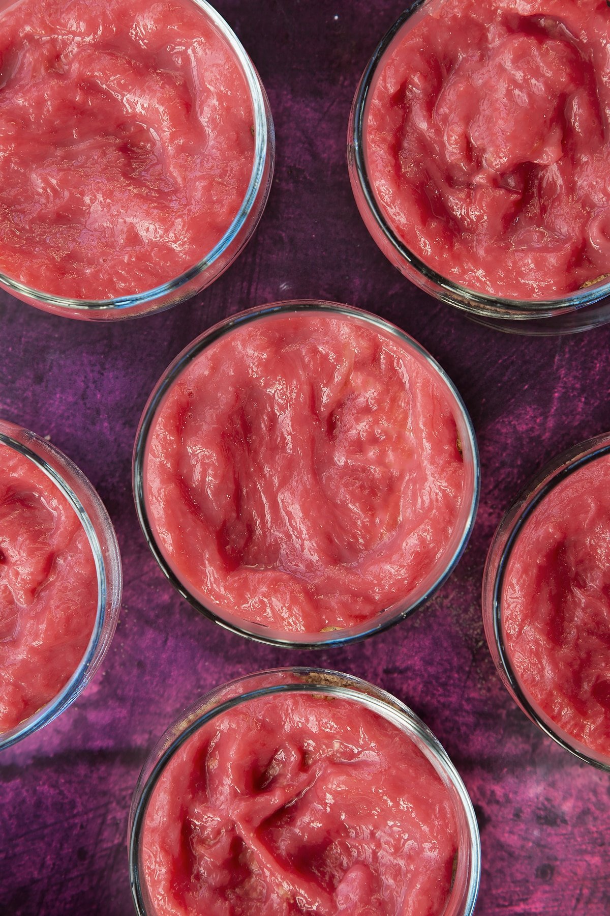 6 clear serving dishes topped with rhubarb puree mixture.