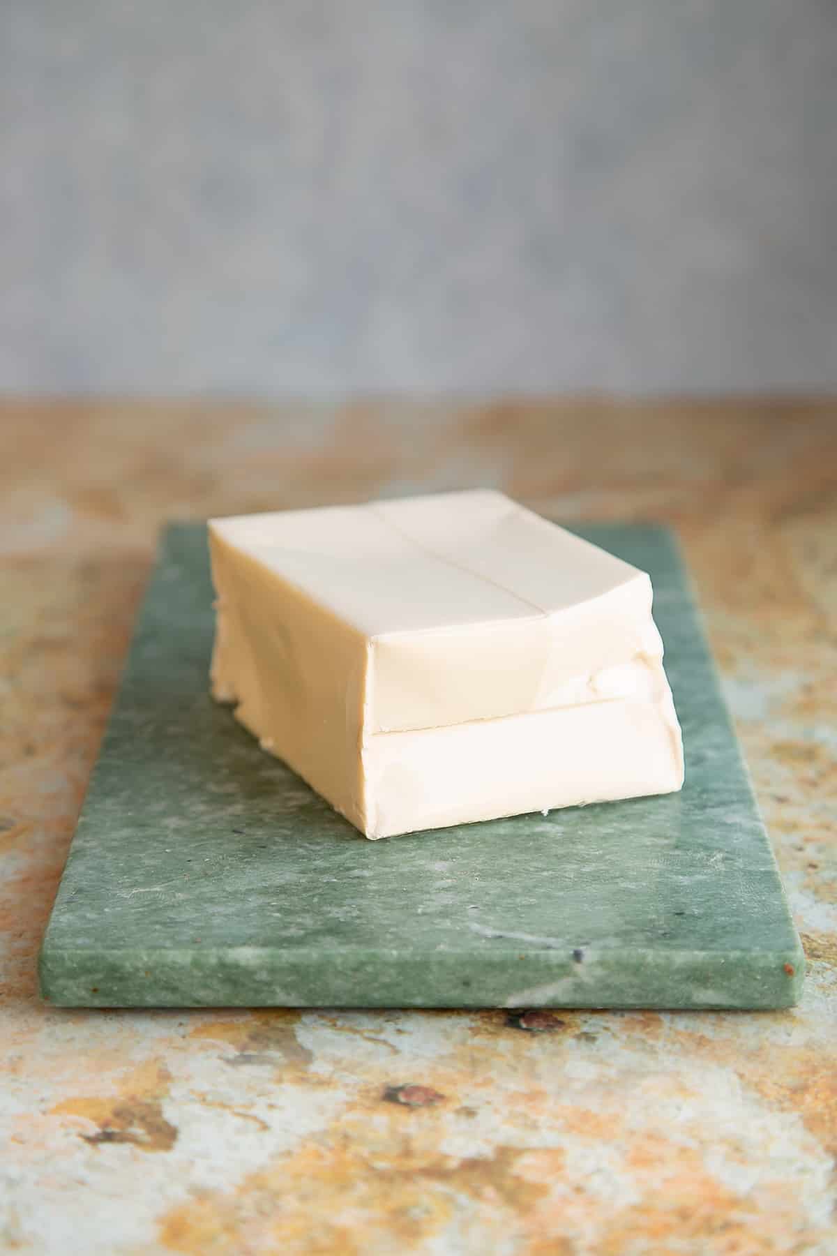 a block of silken tofu on a green marble chopping board.