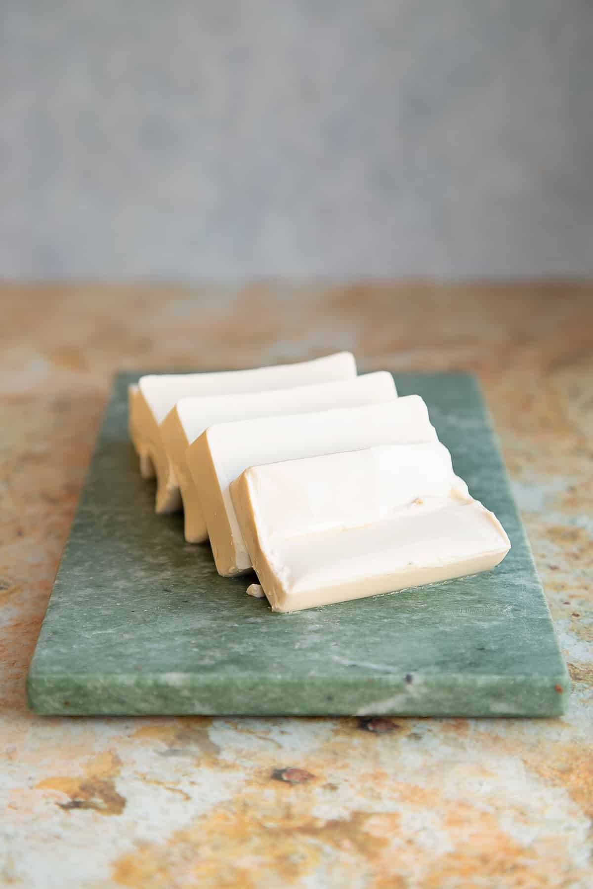 sliced silken tofu on a green marble chopping board.