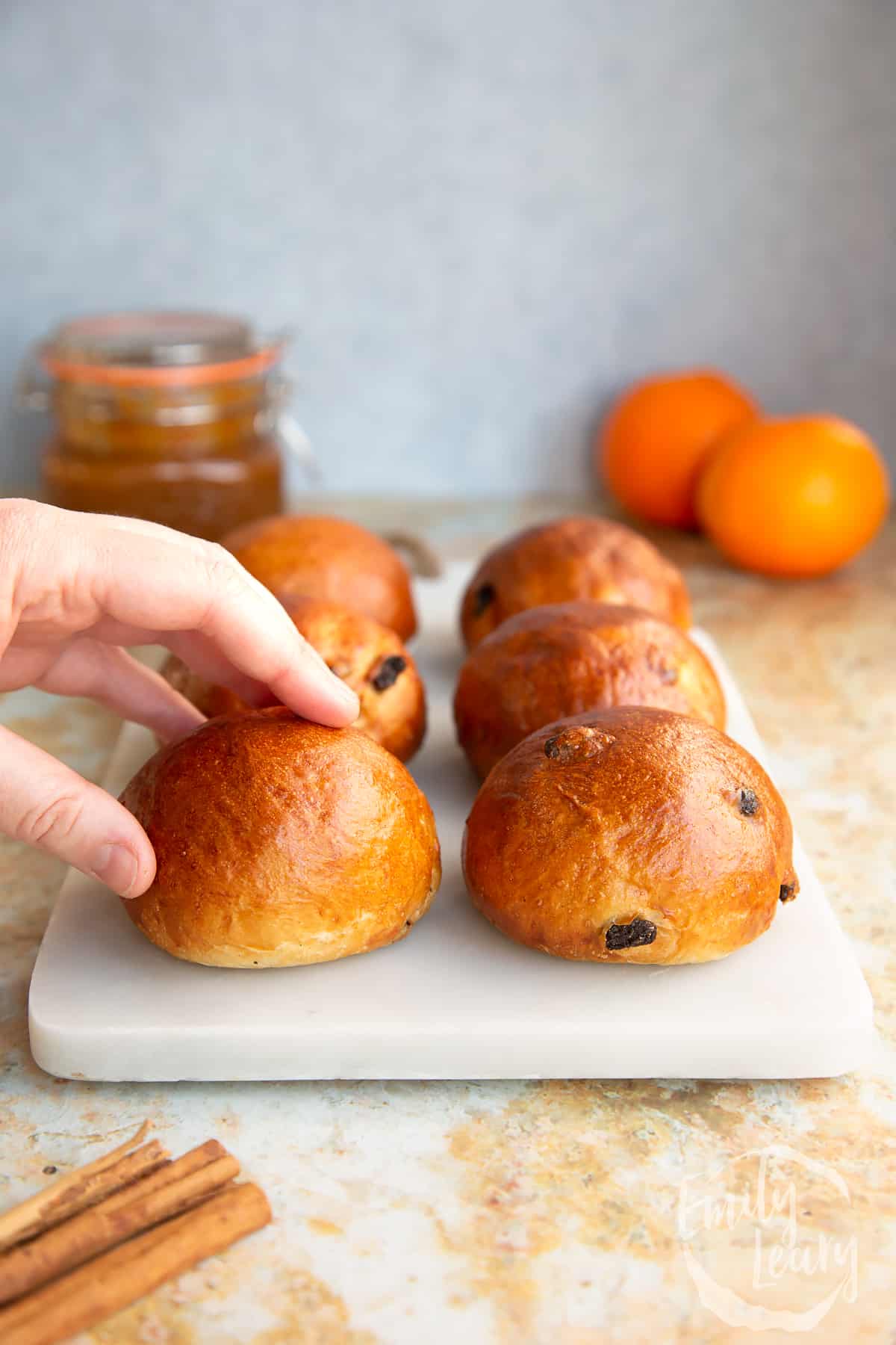 Hand reaching in from the left to grab one of the finished spiced fruit buns.