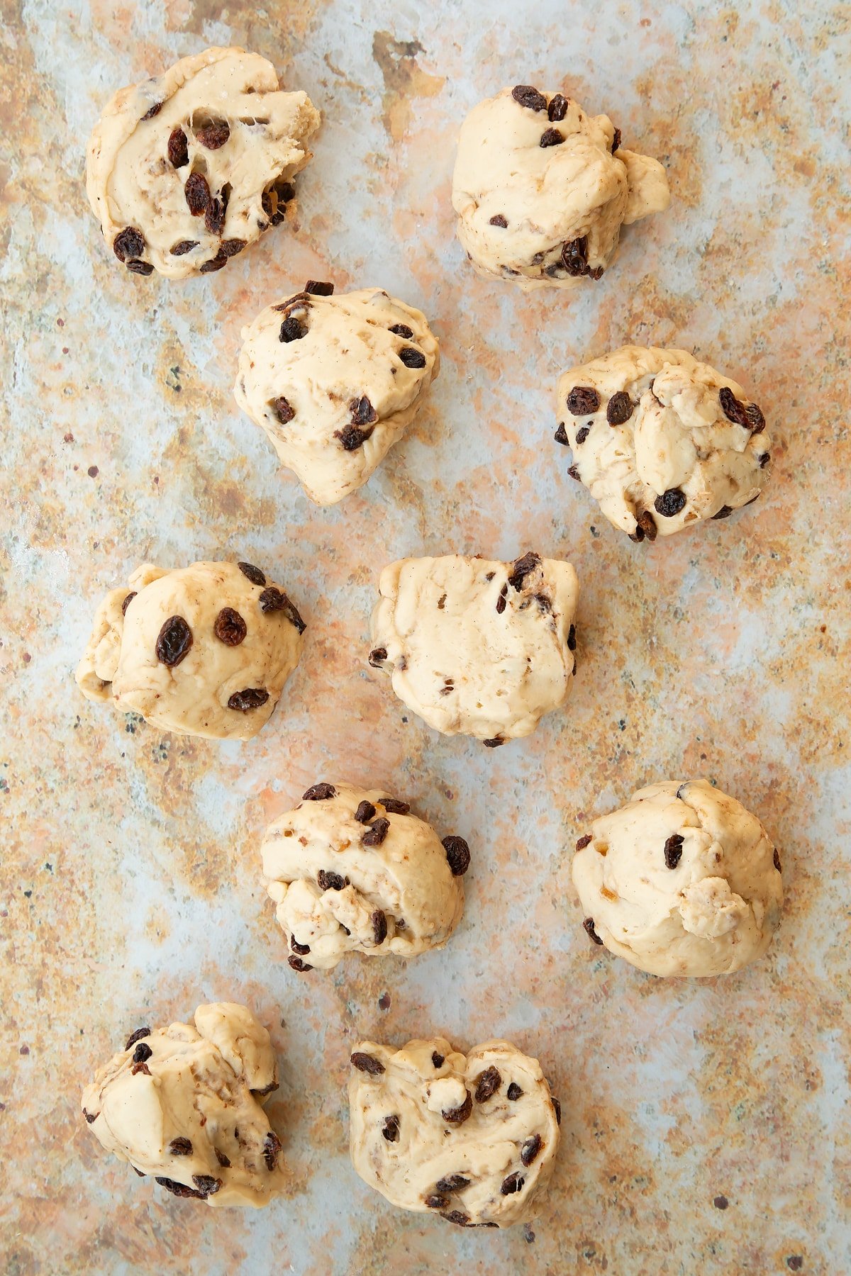 Overhead shot of the spiced fruit buns dough having been split into smaller balls.