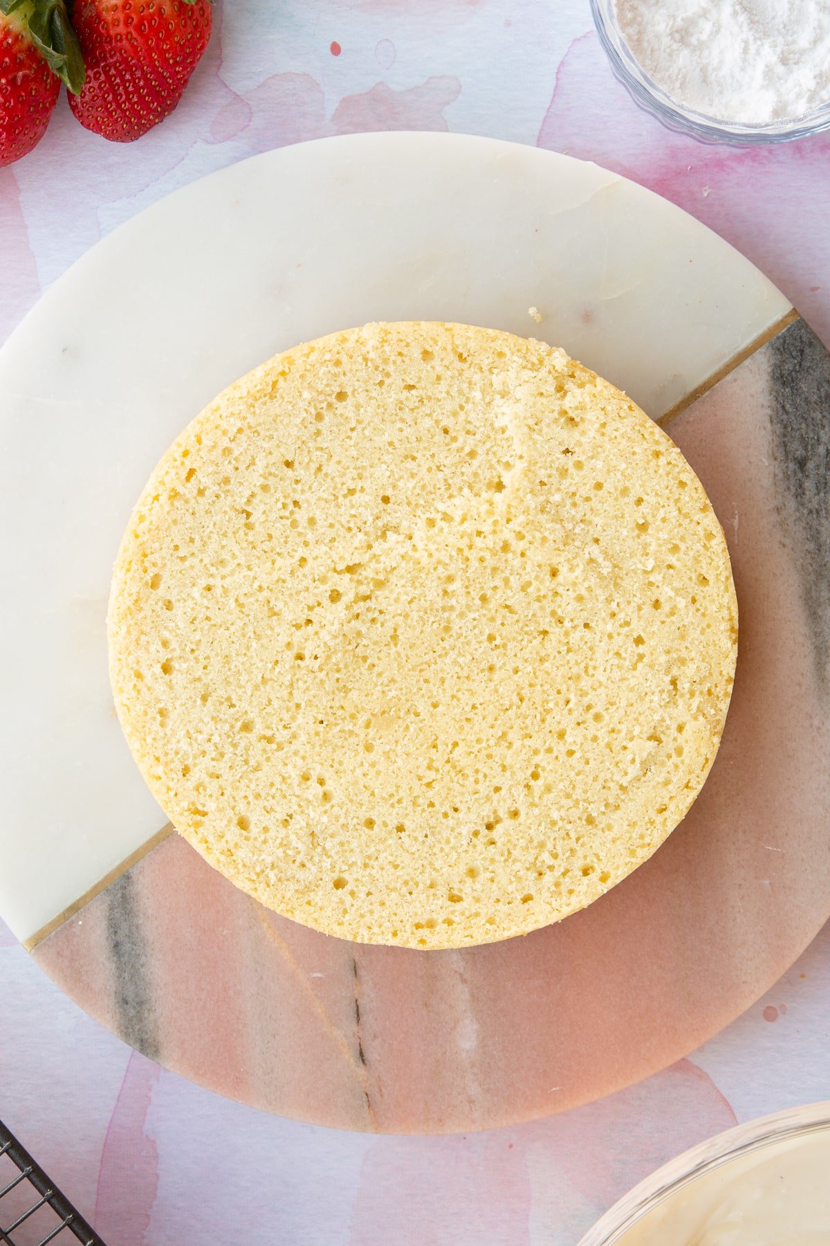 circular sponge cake on a pink marble  board.