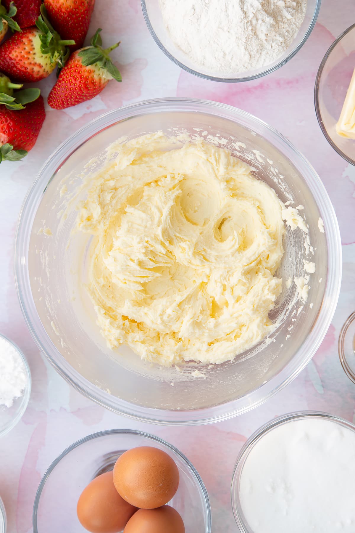 creamed butter and sugar in a large clear bowl with ingredients around the edges