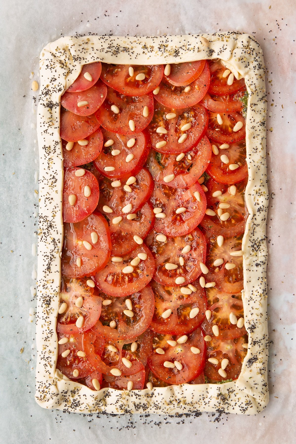 Sprinkling the untoasted pine nuts over the tomatoes.