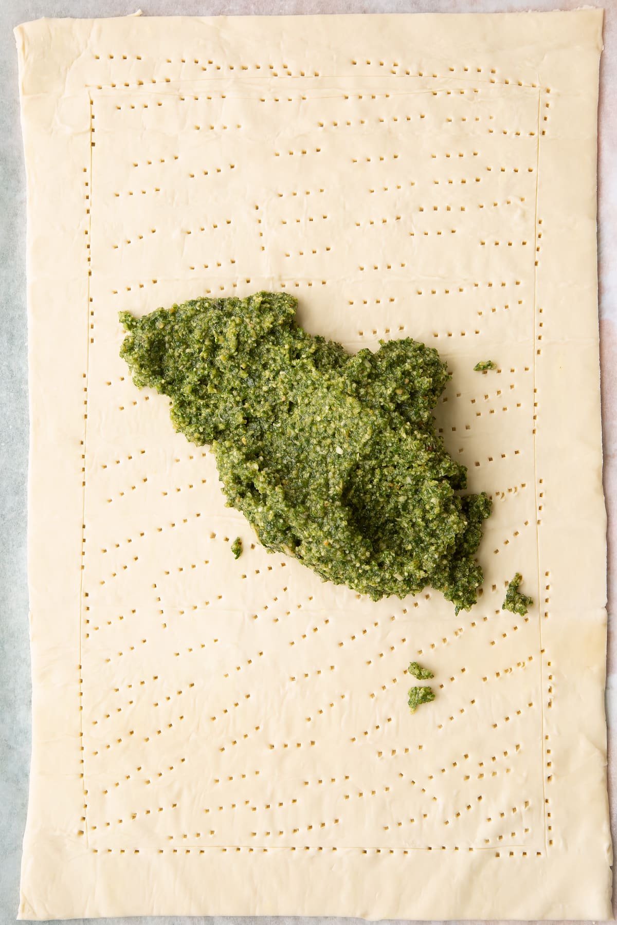 Adding the pesto to the centre of the puff pastry.