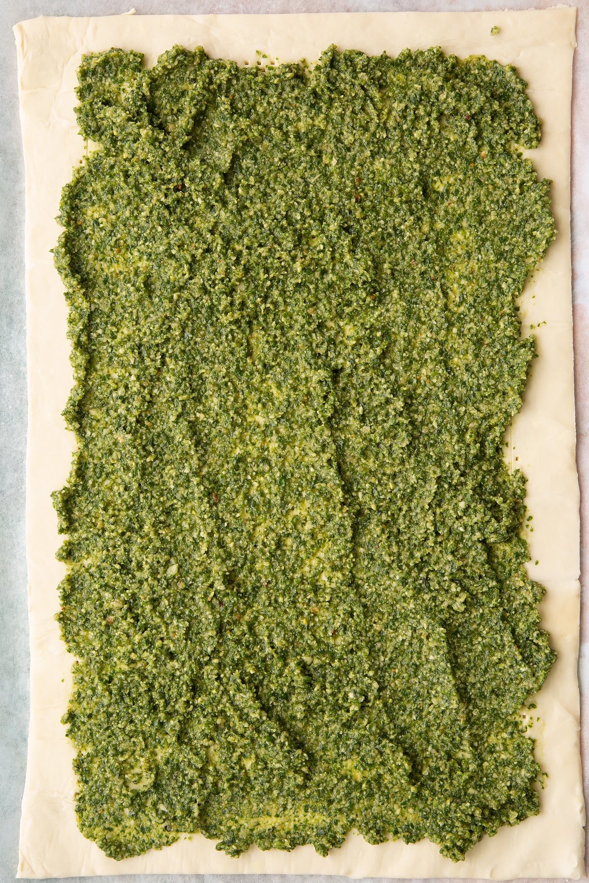 Spreading the pesto across the top of the puff pastry.