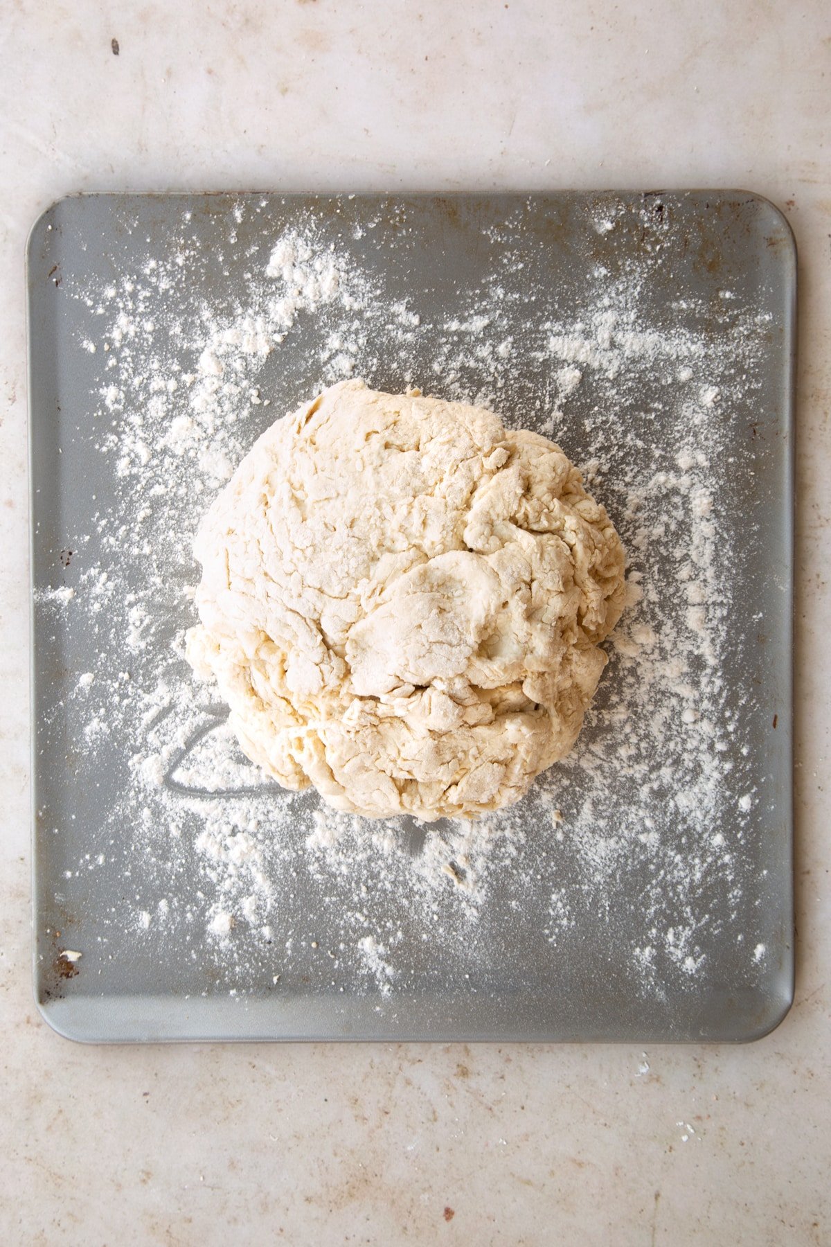 The white spelt soda bread dough on a baking sheet which has been lightly coated in flour. 