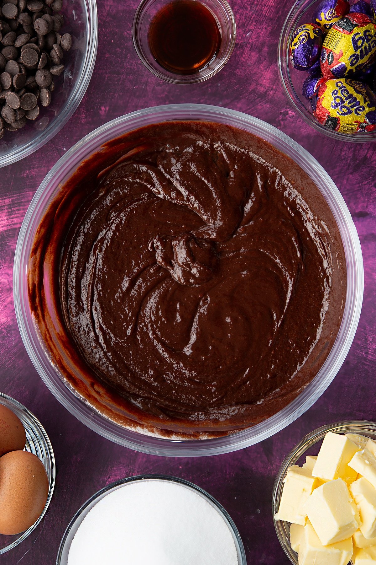 Overhead shot of sugar, butter and chopped dark chocolate in a large, heatproof bowl having been melted together.
