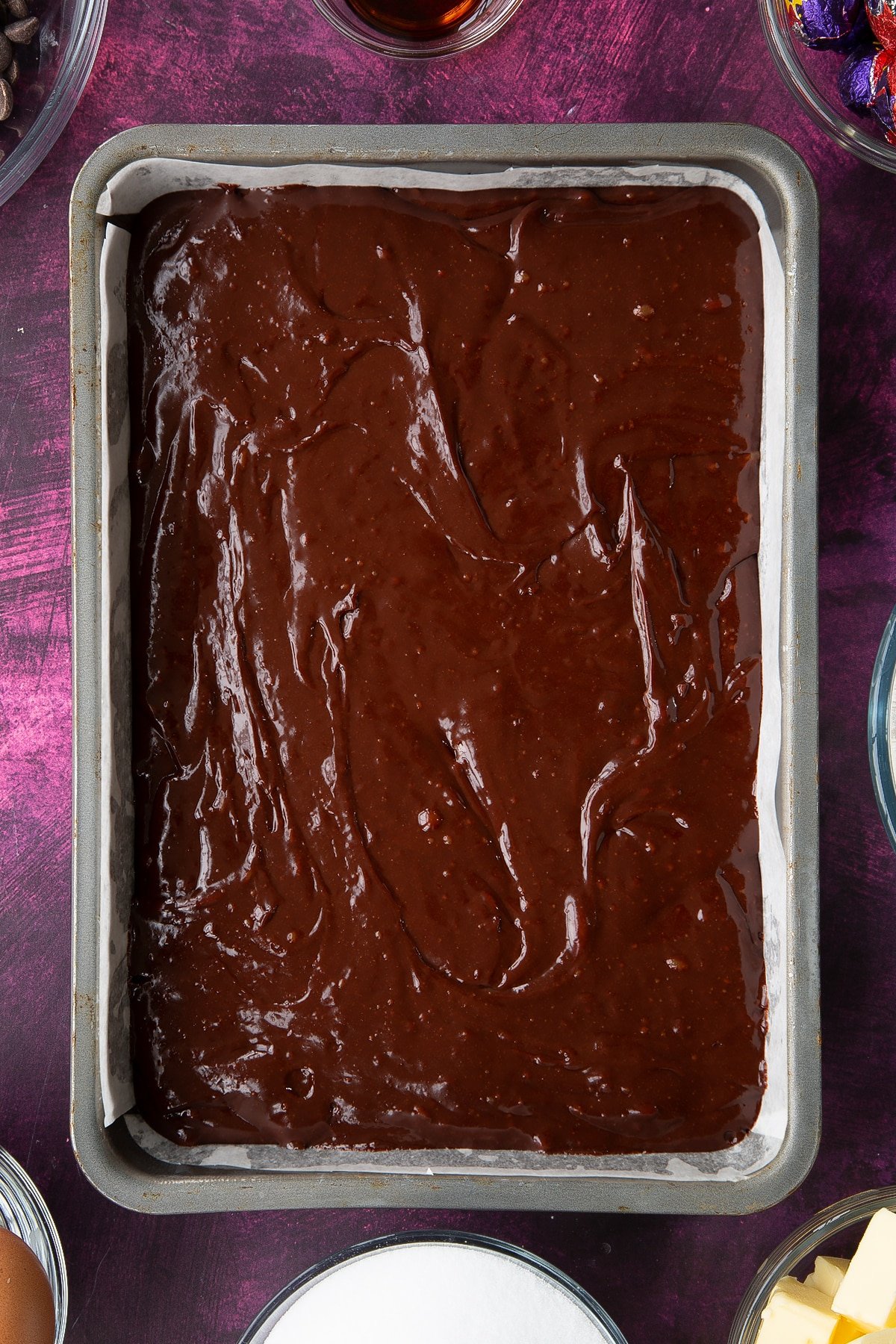 Overhead shot of the reminaing brownie mixture having been poured ontop of the cream eggs in the baking tin. 