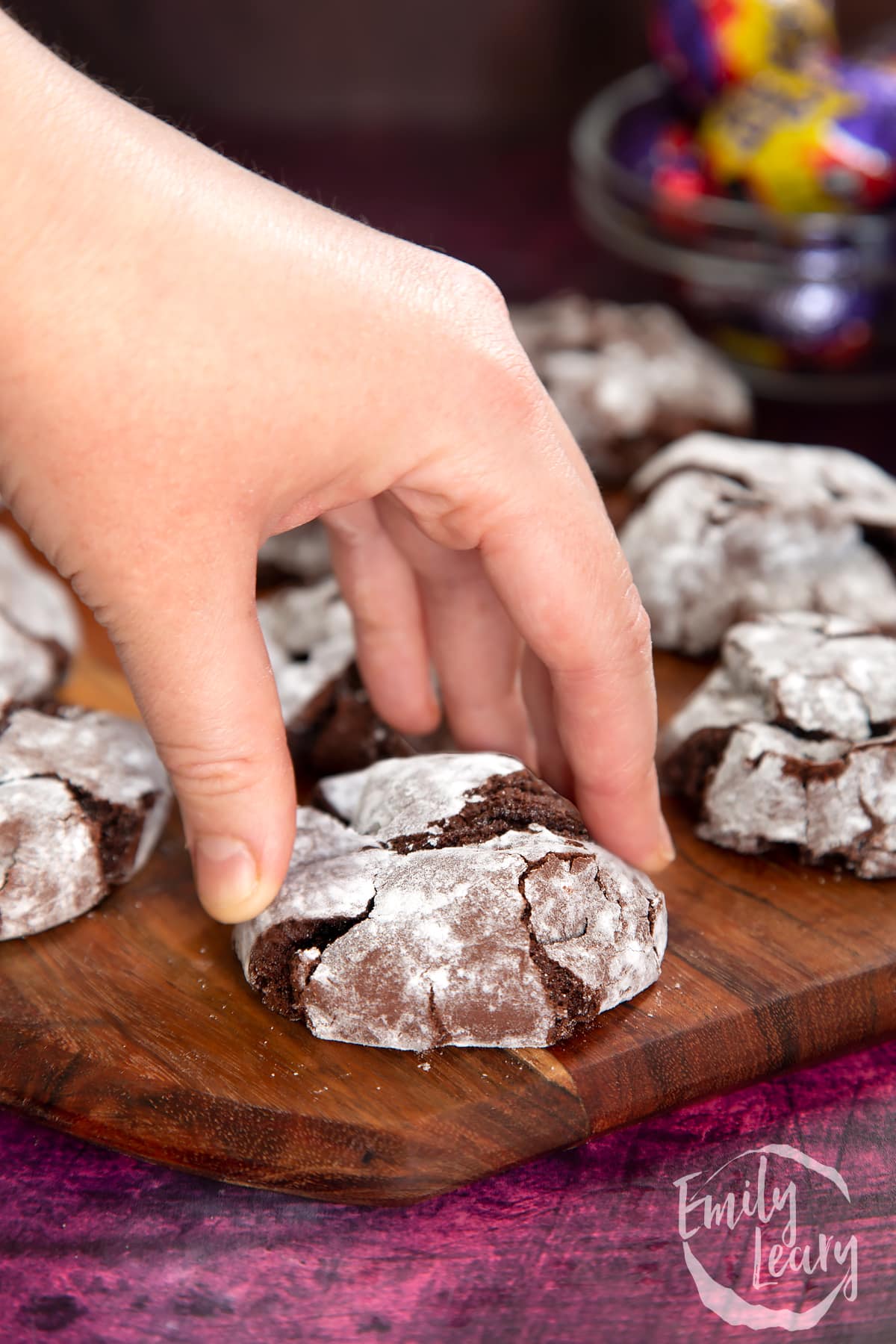 Side on shot of a hand reaching in to grab one of the finished cookies.