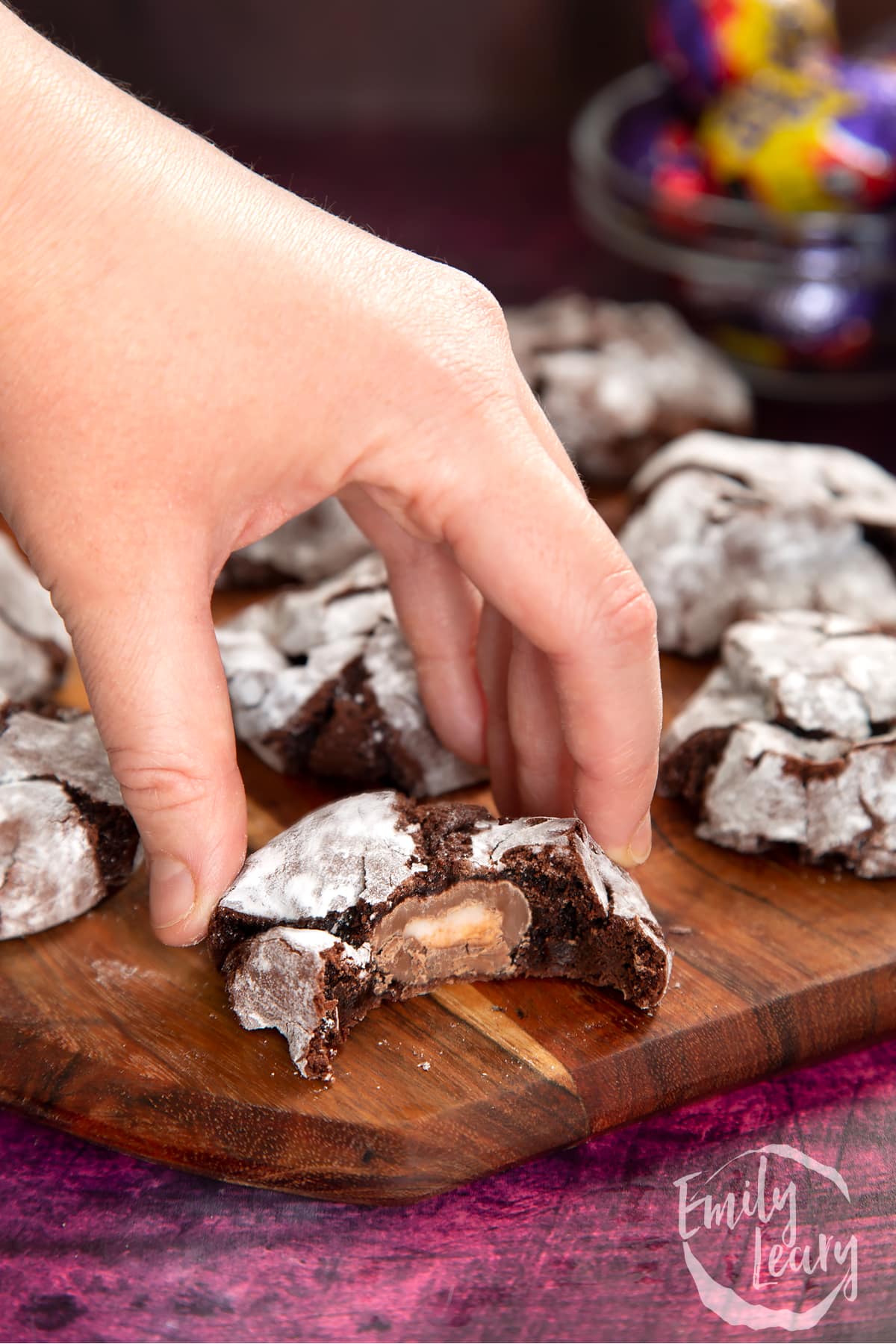 Hand reaching in to grab one of the finished Cadbury Creme Egg cookies. 