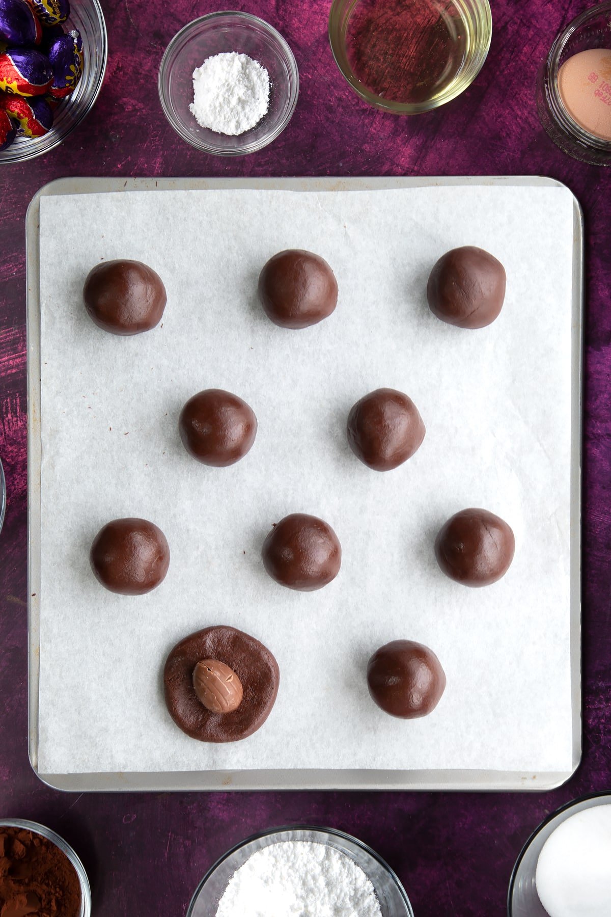 Overhead shot of the dough having been divided into ten equal pieces on a lined baking tray.