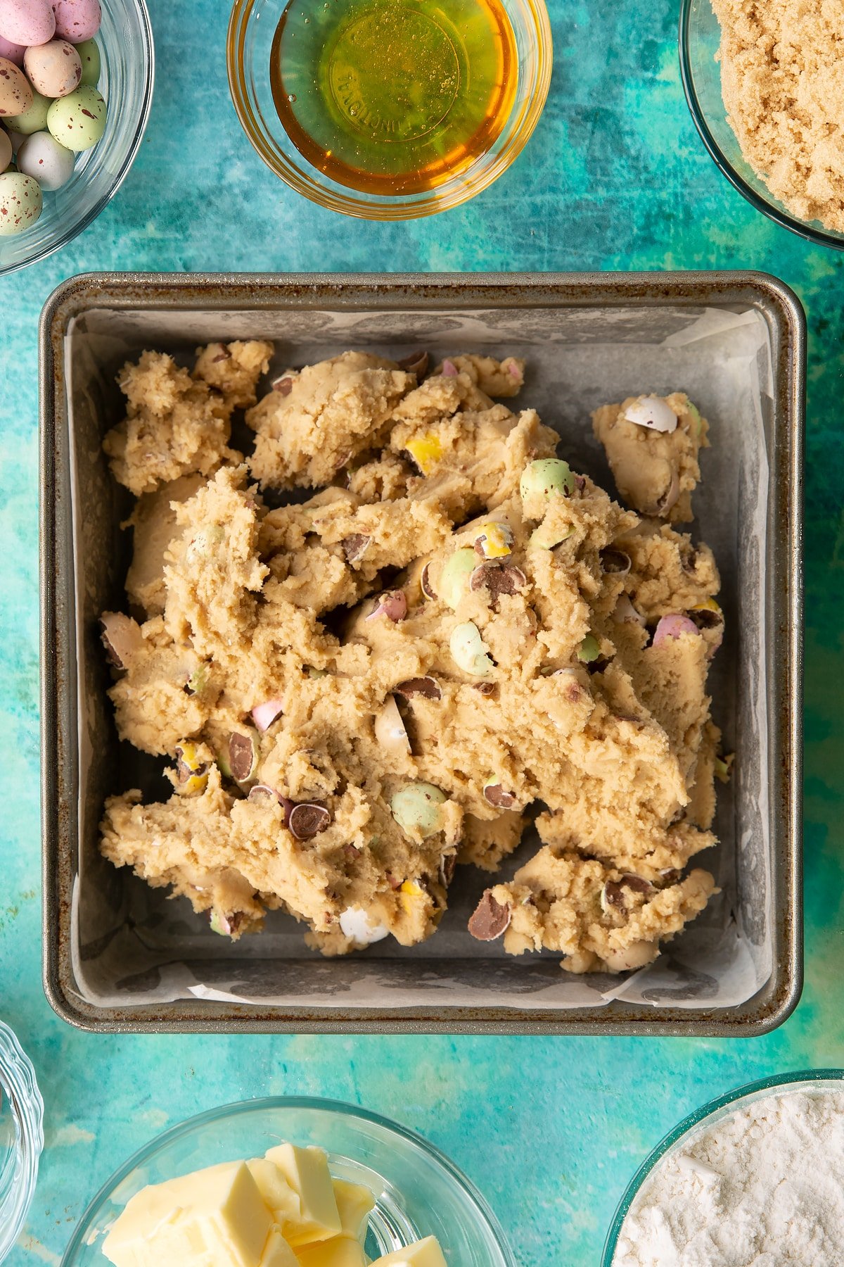 Overhead shot of the cookie dough having been poured into a lined baking tin.