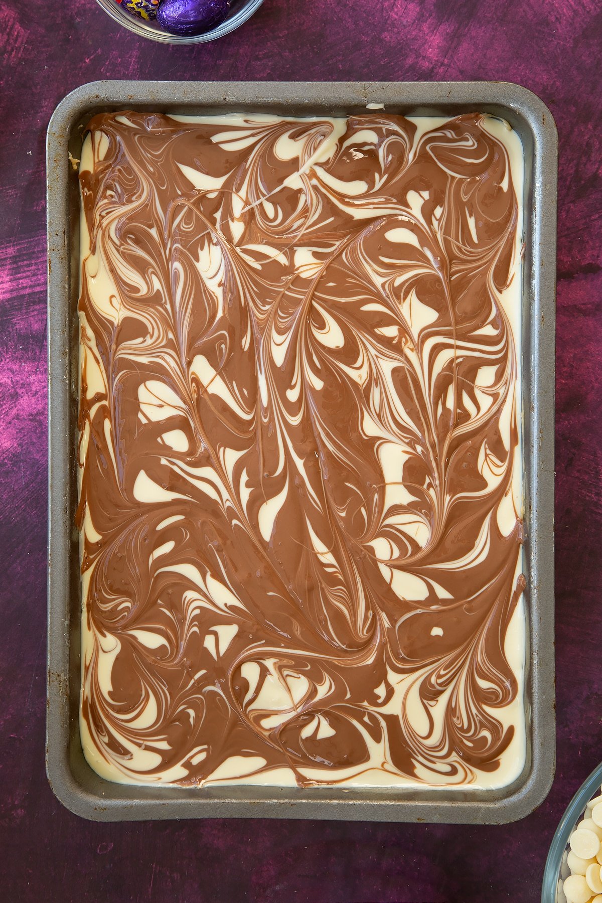 Overhead shot of the baking tin having had the chocolate swirrled into the white chocolate below. 