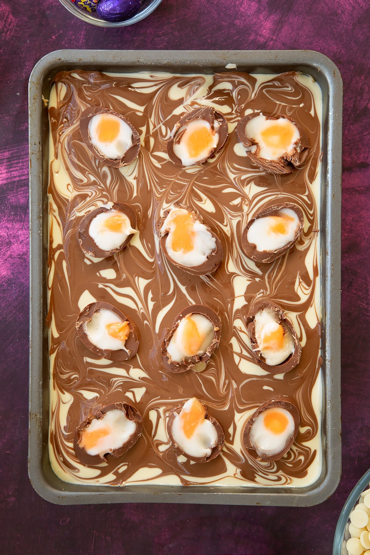 Cut open creme eggs ontop of the white chocolate and milk chocolate topping in the baking tin.