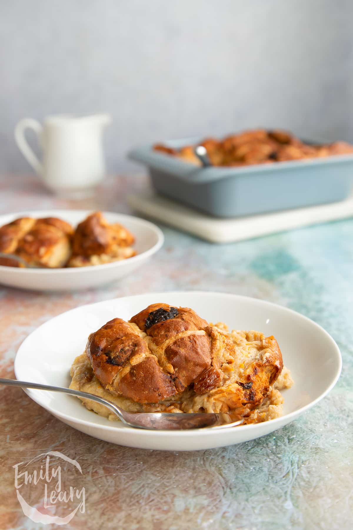 Side on shot of a finished bowl of hot cross bun bread and butter pudding with another bowl in the background.