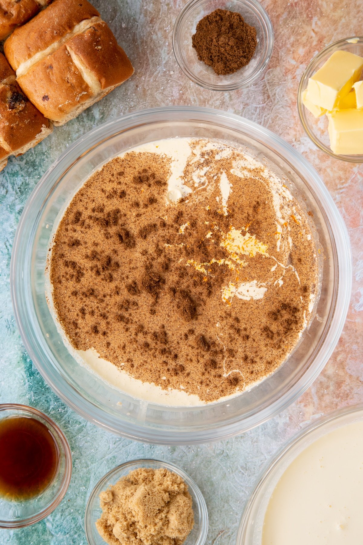 Overhead shot of milk, cream, vanilla extract, eggs, sugar, mixed spice and orange zest in a bowl.