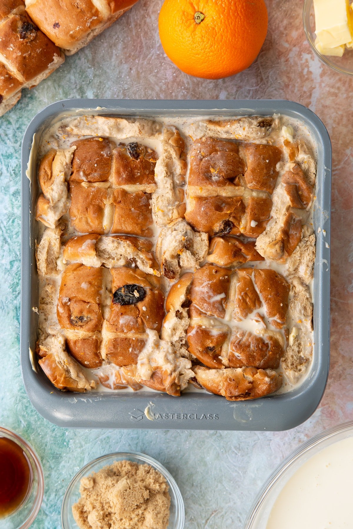 Overhead shot of the tin of hot cross buns after the custard has been added.