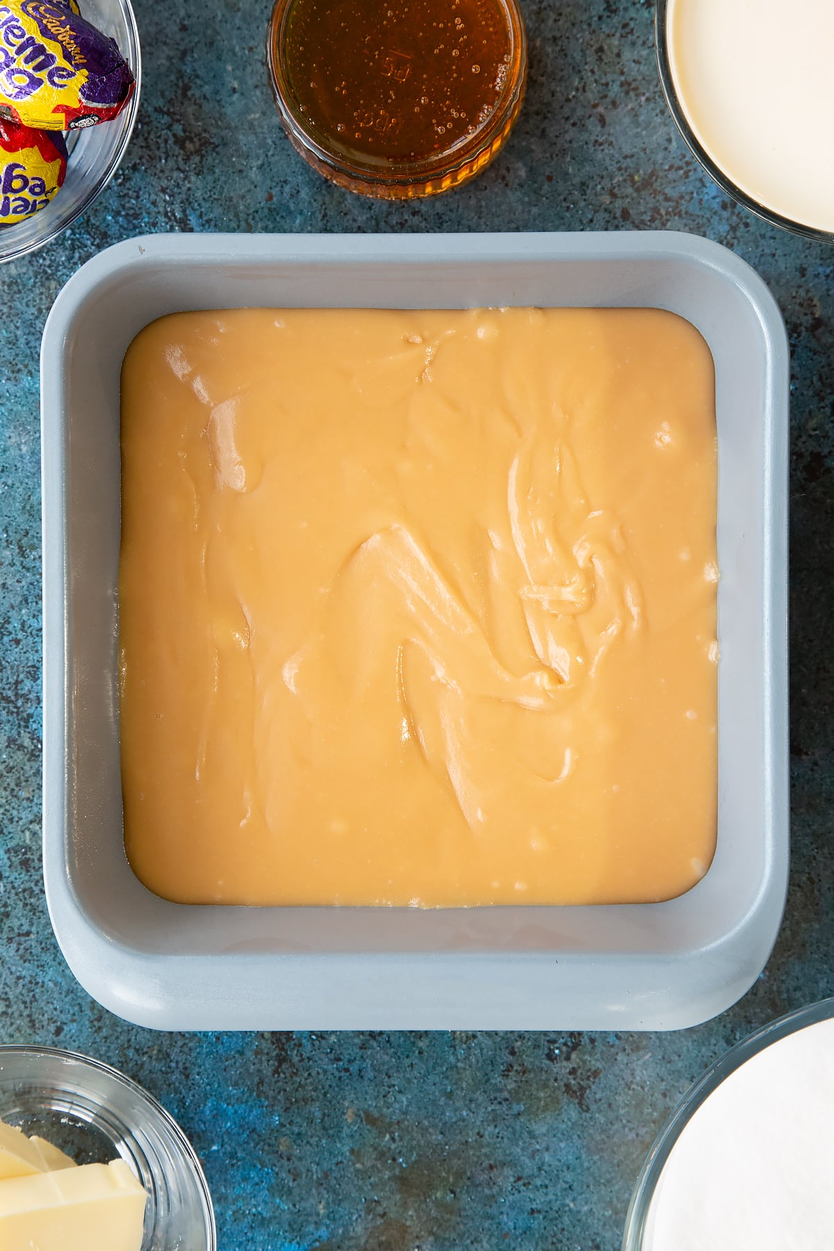 Pouring the fudge into the bottom of a baking tin. 