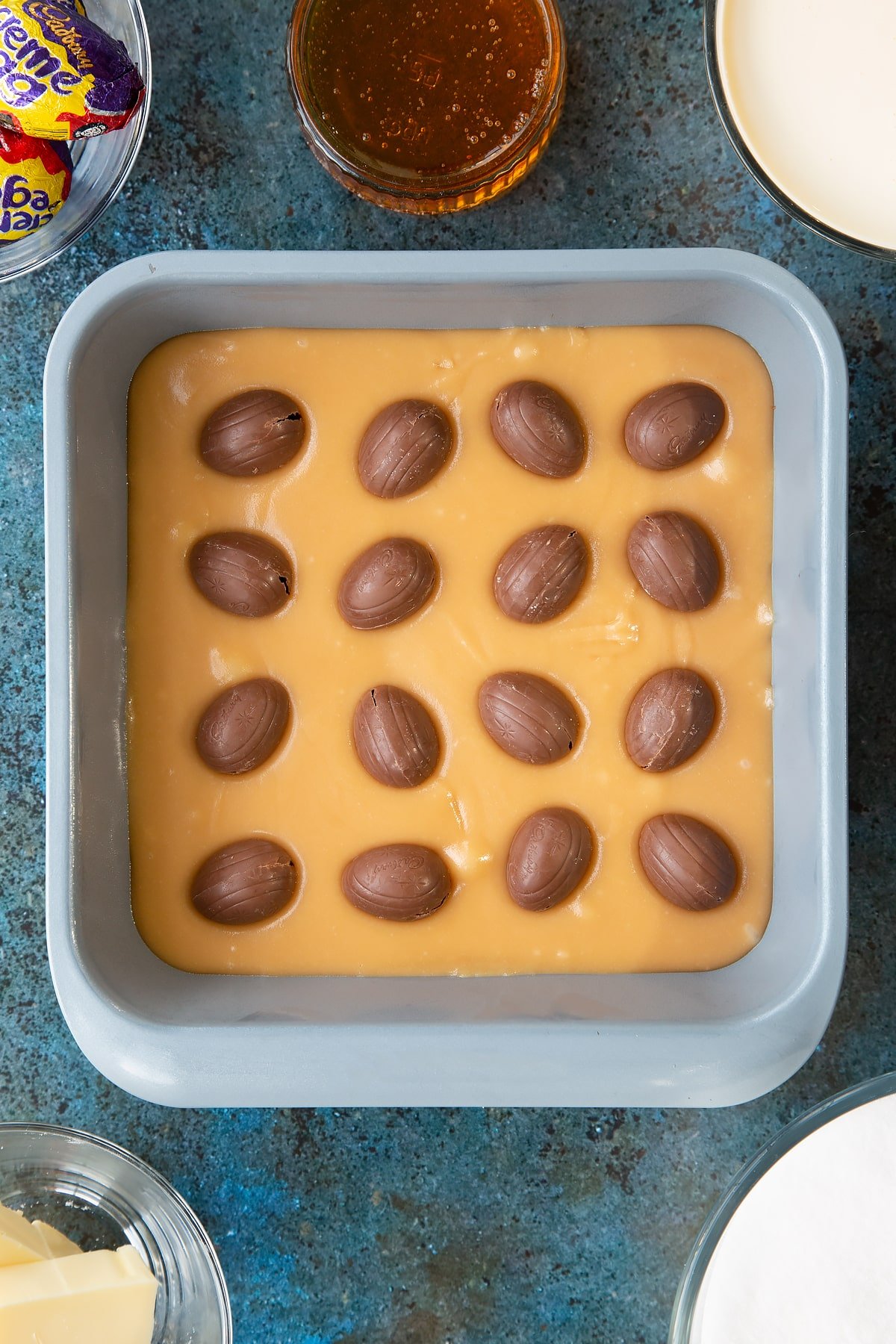 Overhead shot of the baking tin with 16 creme eggs evenly spaced inside. 