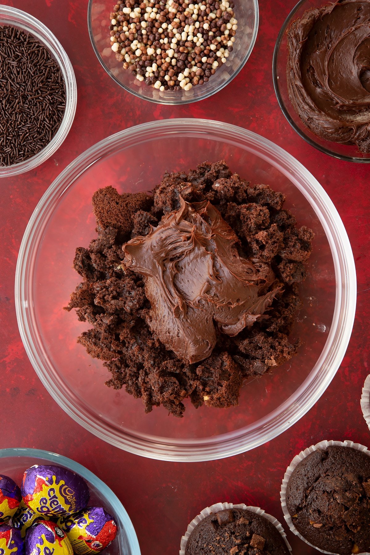 Adding the chocolate fudge frosting to the muffin mixture in a glass bowl.