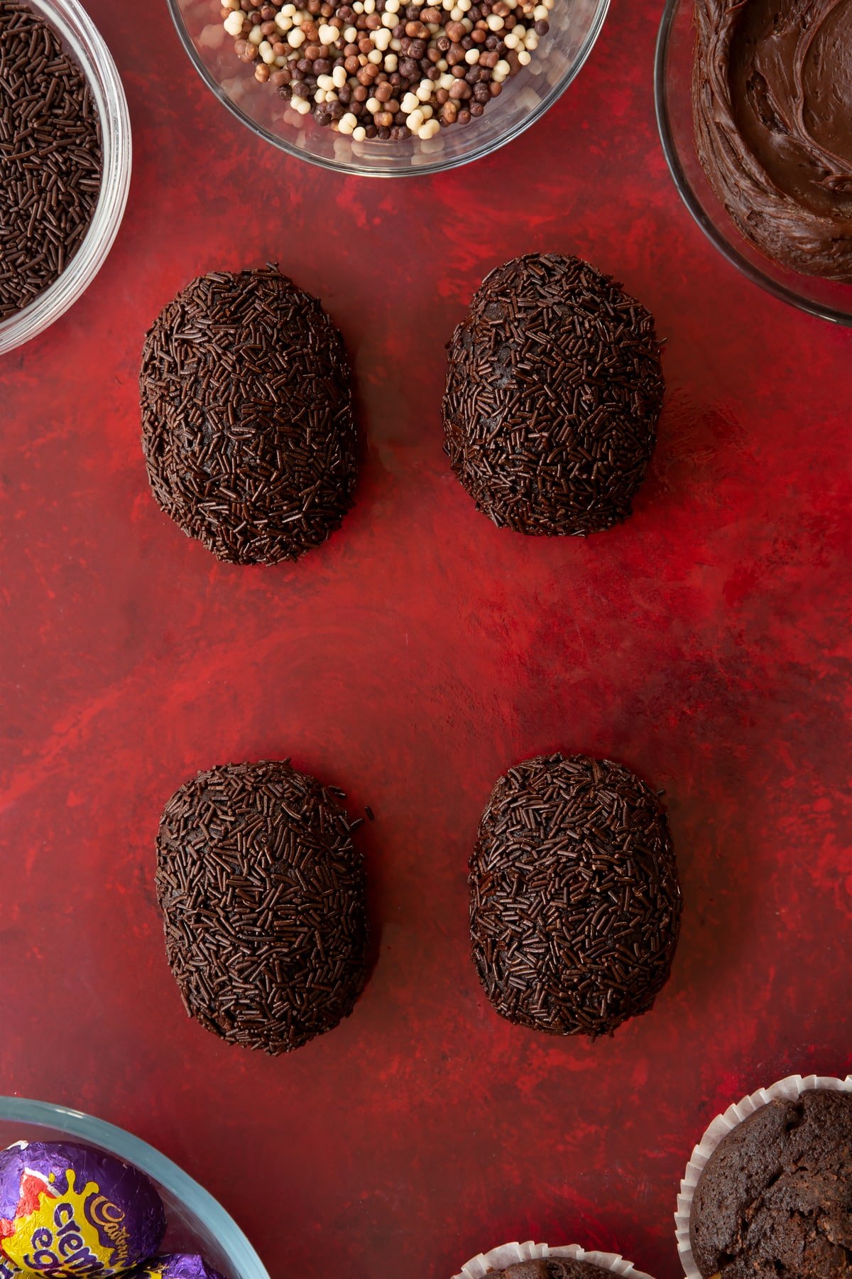 Covering the finished creme Egg Scotch eggs in chocolate sprinkles.