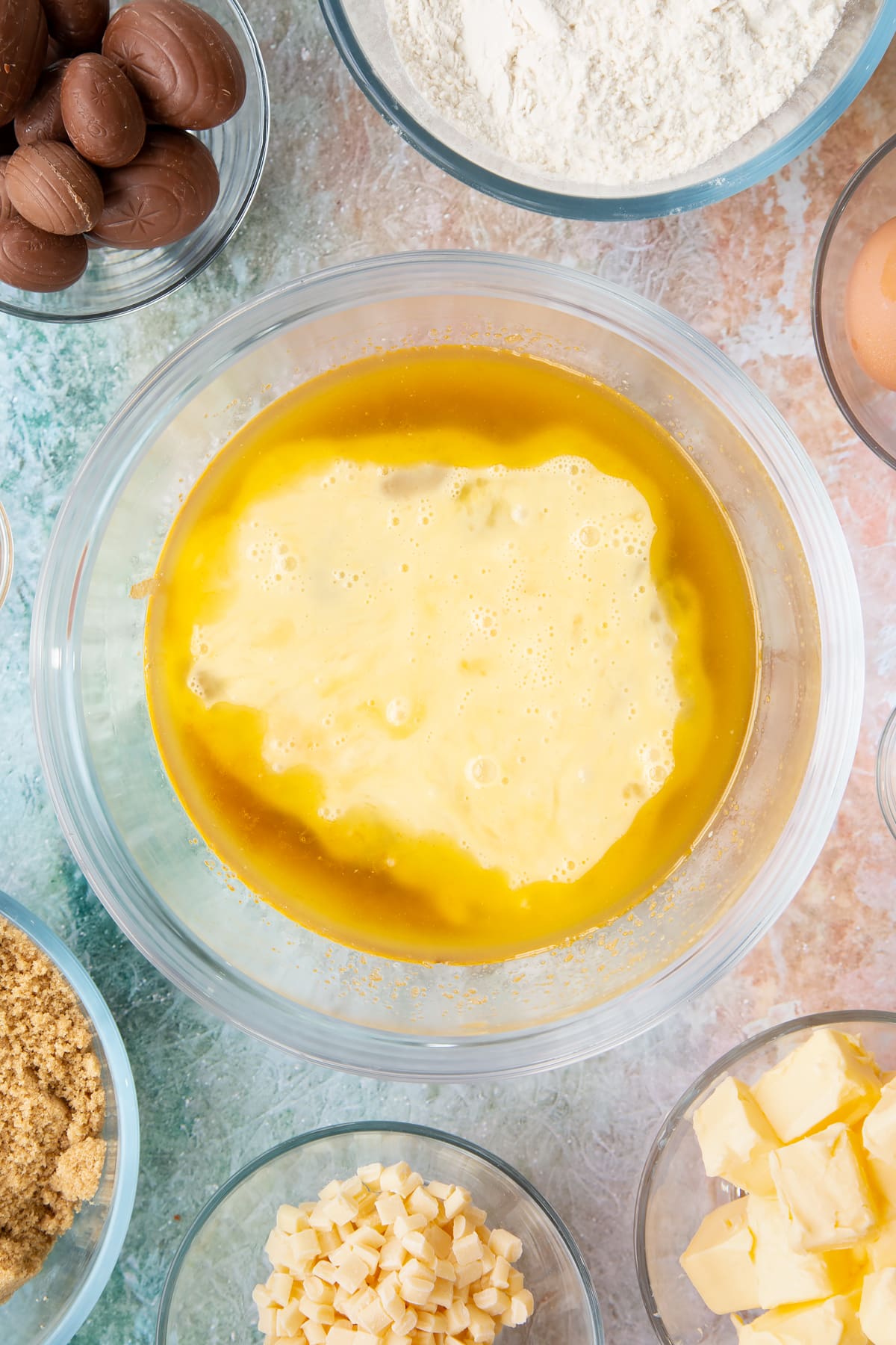 Overhead shot of a mixing bowl with eggs, melted butter and sugar.