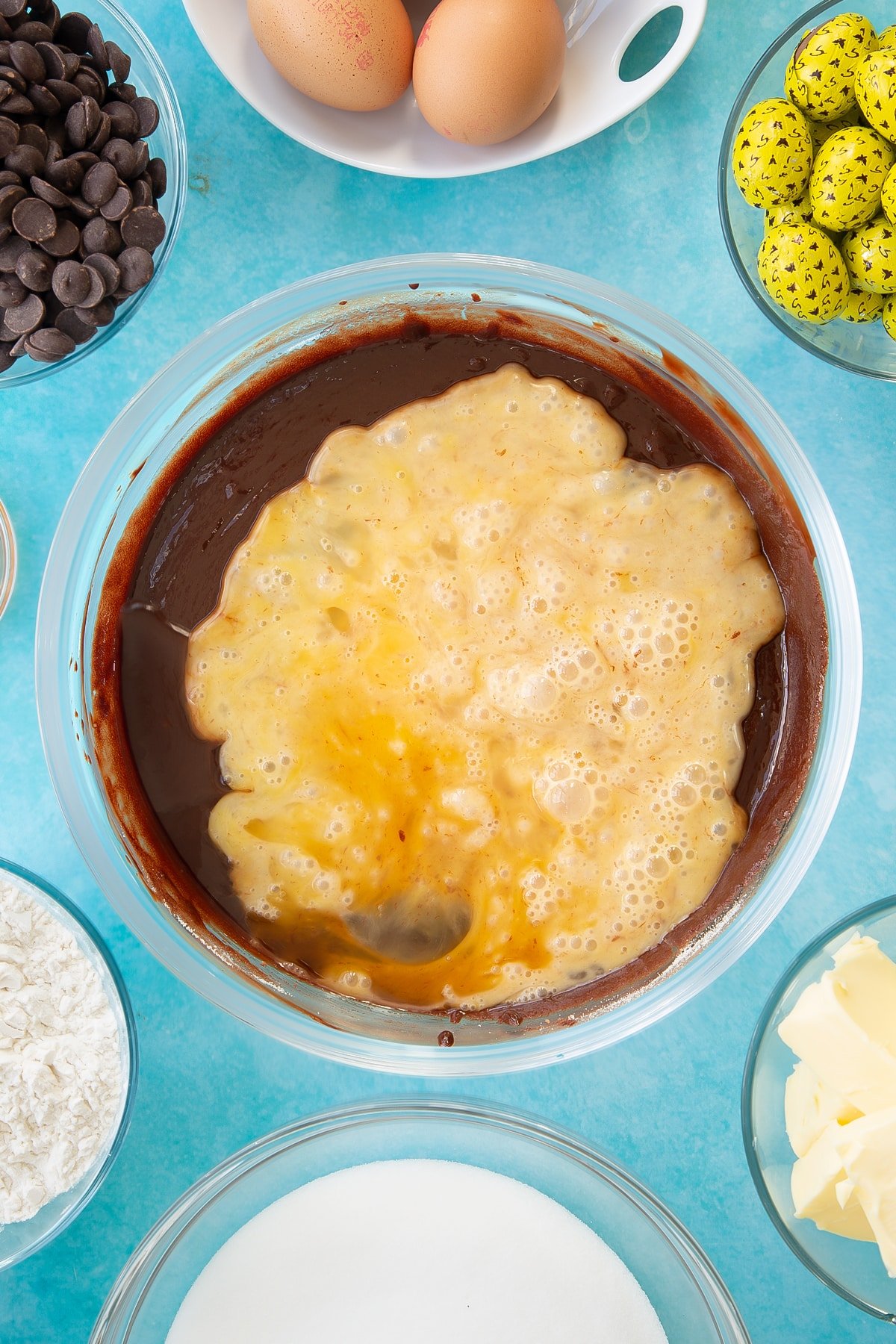 Adding eggs and vanilla to the easter brownies wet mixture in a mixing bowl.