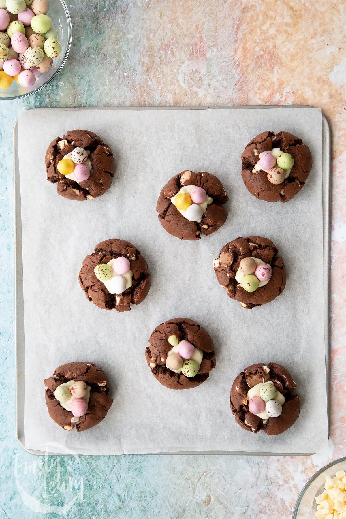 Overhead shot aftre three mini eggs have been added to the white chocolate and cream cheese mixture atop the Easter cheesecake cookies.