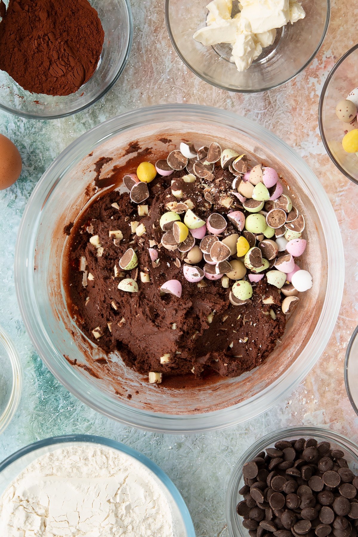 Adding the chopped mini eggs to the Easter cheesecake cookie mixture bowl.