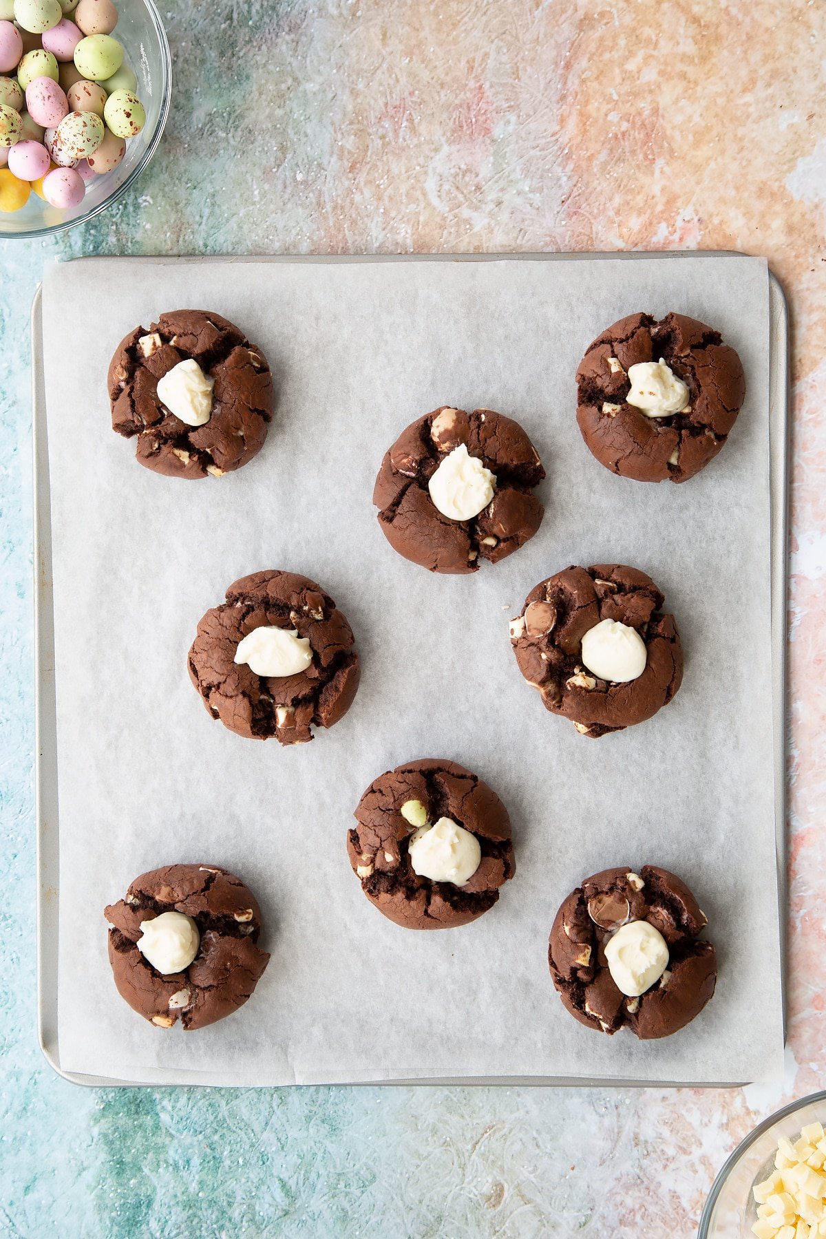 adding a teaspoon of the white chocolate and cream cheese mixture into the well inside the Easter cheesecake cookies.