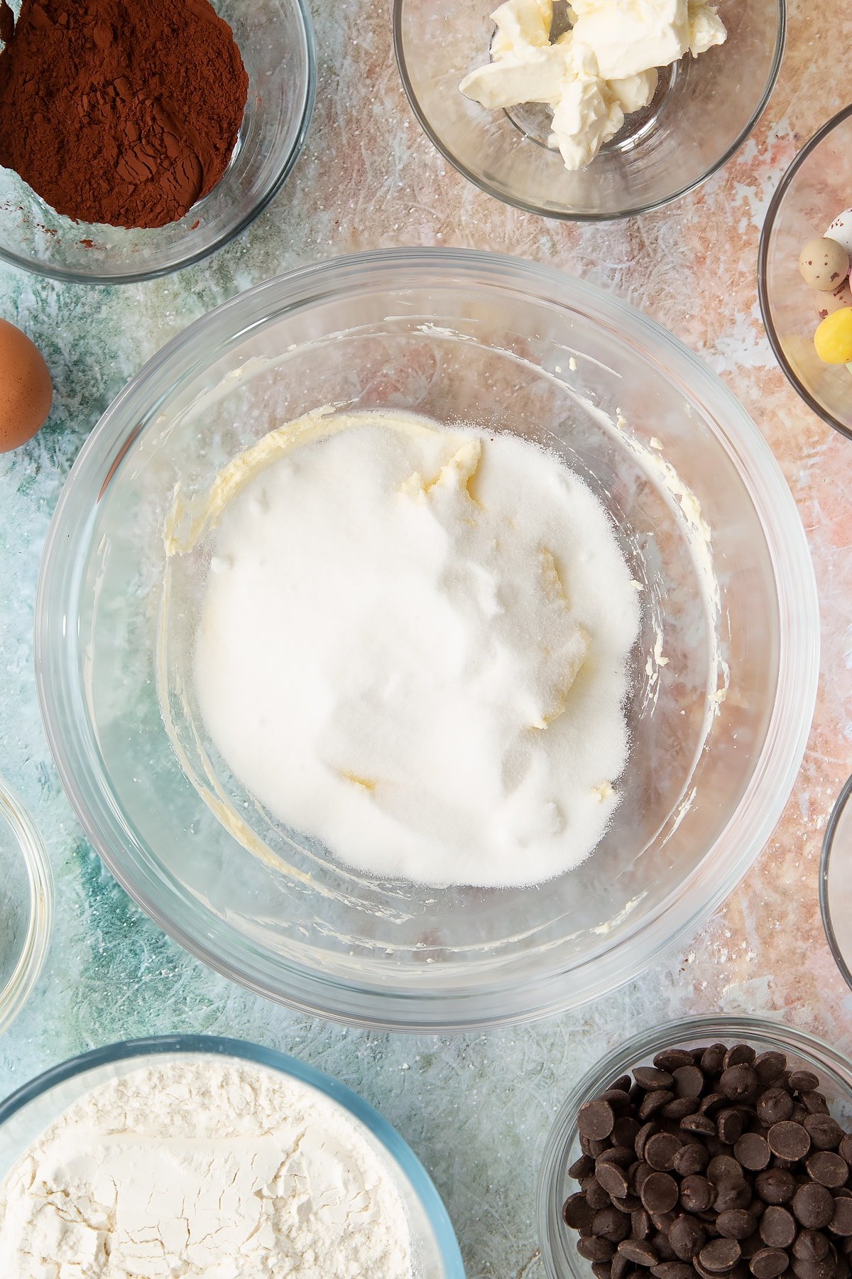 Adding sugar to the mixing bowl of ingredients for the Easter cheesecake cookies.