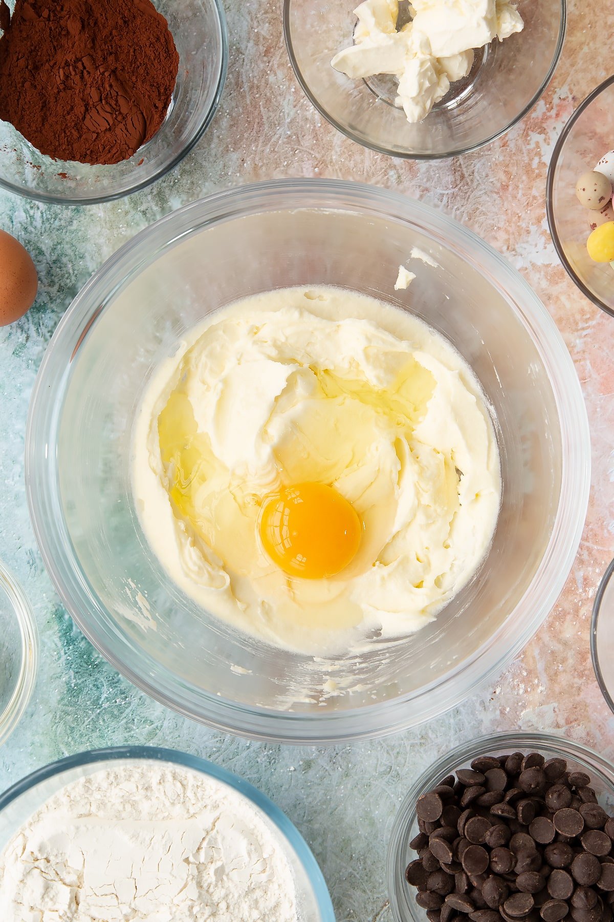 Adding an egg to the Easter cheesecake cookies wet ingredients inside a mixing bowl.