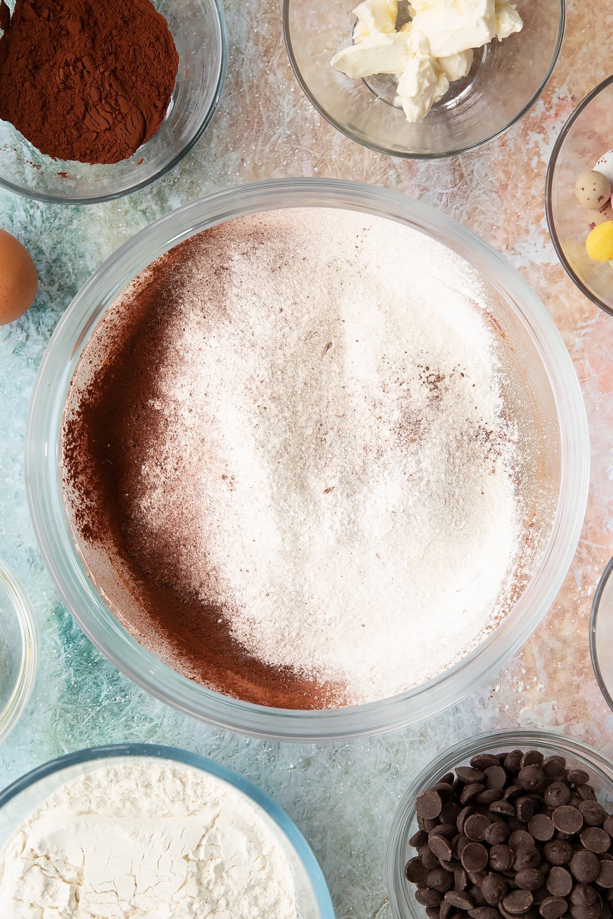 Adding flour, bicarbonate of soda, baking powder, salt and cocoa powder to the mixing bowl of ingredients for the Easter cheesecake cookies.