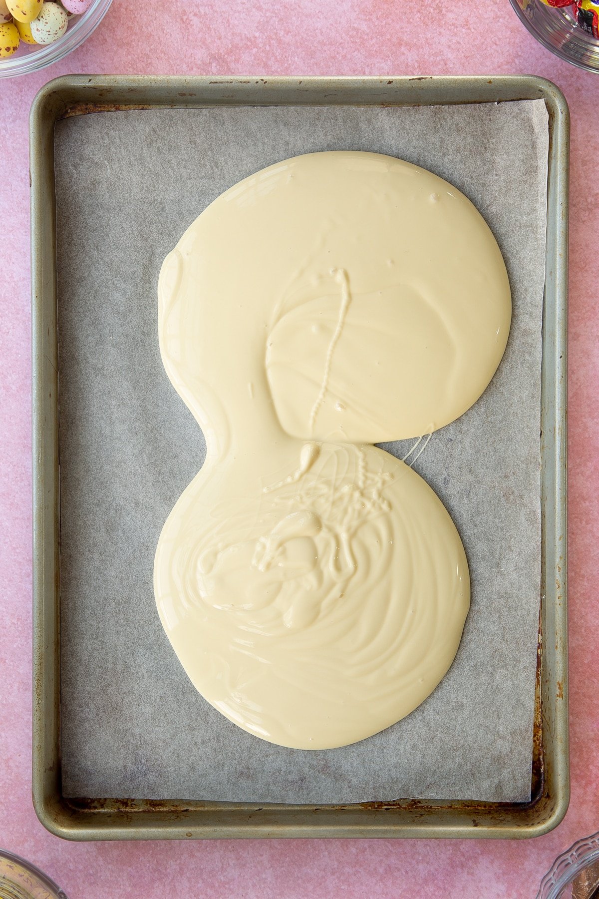 Melted white chocolate being poured onto a baking tray.