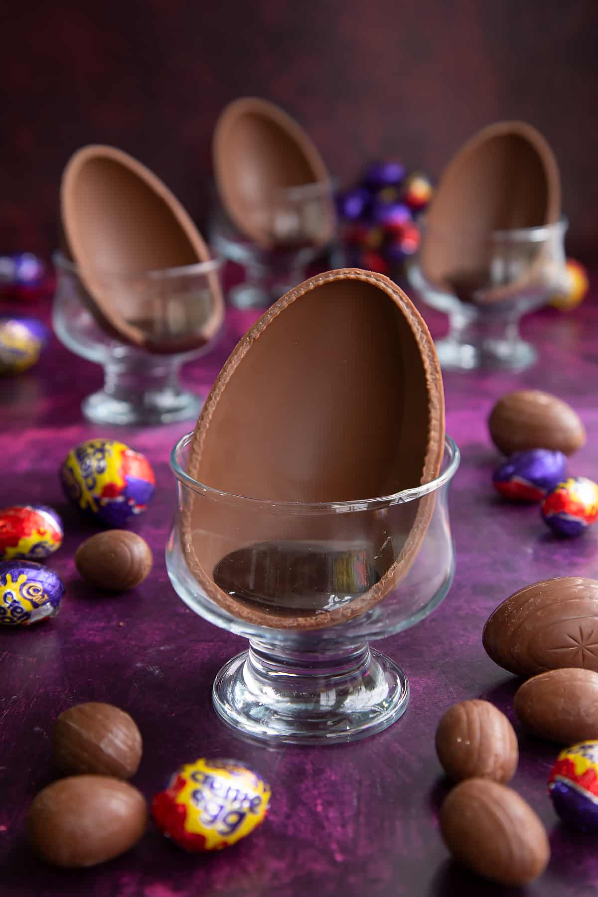 Half an Easter egg in a decorative bowl with melted chocolate sauce.