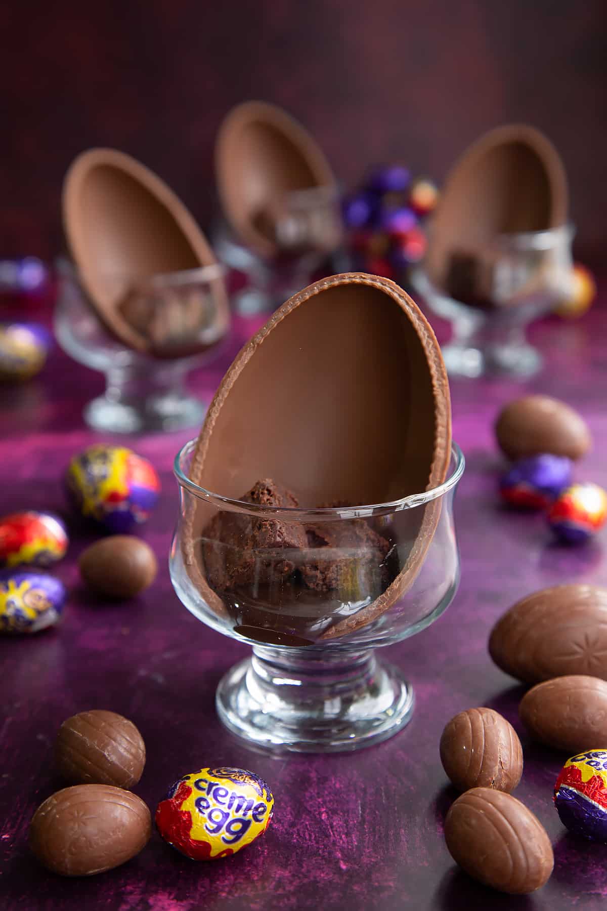 Half an Easter egg in a decorative bowl with melted chocolate and three brownie bites.